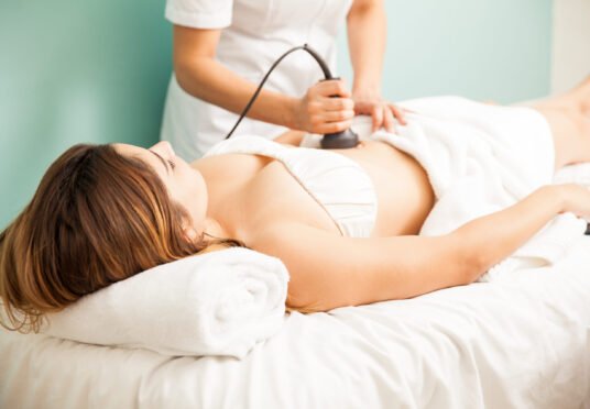 Female therapist giving a reductive and reaffirming treatment to a client and focusing on her belly