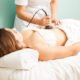 Female therapist giving a reductive and reaffirming treatment to a client and focusing on her belly